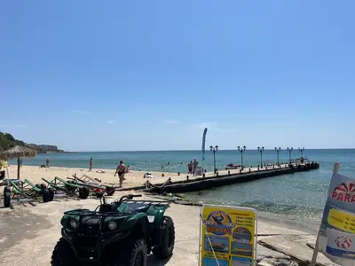 a quad bike parked on a beach with a pier at Apartament Studio Bułgaria Garden Of Eden in Sveti Vlas