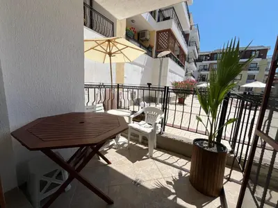 a balcony with a wooden table and chairs and a potted plant at Apartament Studio Bułgaria Garden Of Eden in Sveti Vlas