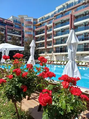 a swimming pool with red flowers and white umbrellas at Admiral Plaza 35 -studio-Sunny Beach in Sunny Beach