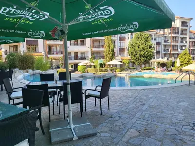 a table and chairs with an umbrella in front of a swimming pool at Vineyard luxery spa resort in Kableshkovo