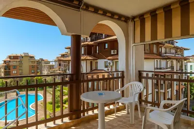 a balcony with a table and chairs and a pool at Olymp SkyView Apartment in Sveti Vlas