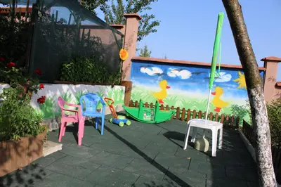 a patio with chairs and a mural of ducks at Къща за гости АВЛИГА in Varna City