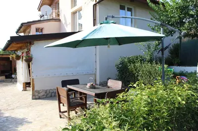 a table with a green umbrella on a patio at Къща за гости АВЛИГА in Varna City