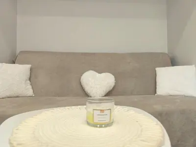 a heart pillow on a couch with a candle on a table at Apartment Compass- Super Center Burgas in Burgas City
