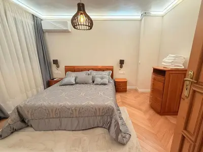 a bedroom with a bed and a pendant light at Victoria- две спални делукс до Морската градина и центъра in Burgas City