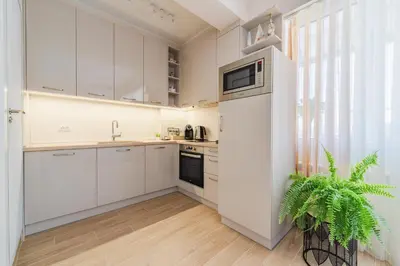 a white kitchen with a refrigerator and a plant at Luxury Seaside Apartment in Varna City