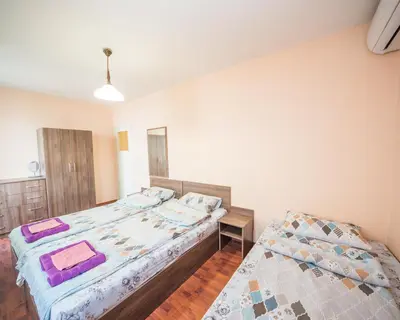 a bedroom with two beds and a table in it at LAZUR - Nice Sunny Flat in Burgas City