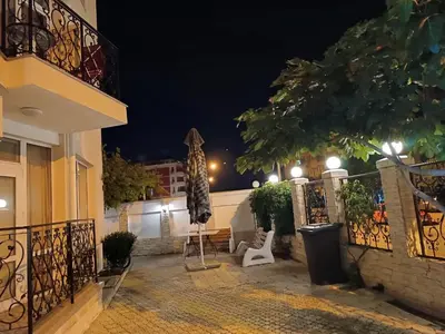 a patio at night with a table and an umbrella at Sunny Beach Apartment, Kokiche Hotel - white building Liliya in Sunny Beach