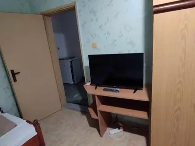 a room with a tv on a wooden desk with a dresser with a television at Къща за гости дом Попови Черноморец in Chernomorets