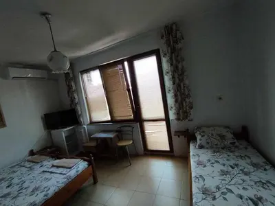a bedroom with a bed and a desk and two windows at Къща за гости дом Попови Черноморец in Chernomorets