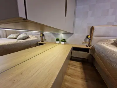 a room with two beds and a wooden floor at Delux Apart Vulchevi with Parking in Burgas City