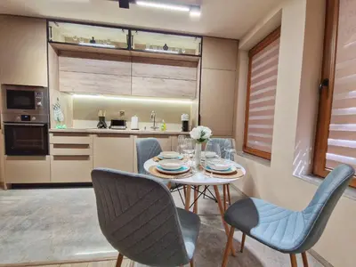 a dining room with a table and chairs and a kitchen at Delux Apart Vulchevi with Parking in Burgas City