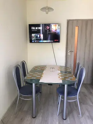 a dining room table with chairs and a tv on the wall at Ssenyange Sea View Apartment in Varna City