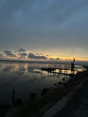 a sunset over a lake with a dock in the water at Studiosaltsea in Pomorie