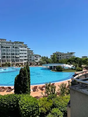 a large swimming pool with chairs and buildings at Private apartments Ravda-Emerald in Ravda