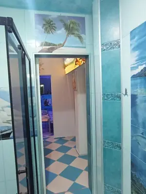 a bathroom with a glass door with a palm tree on the wall at Apartament ALBATROS in Burgas City