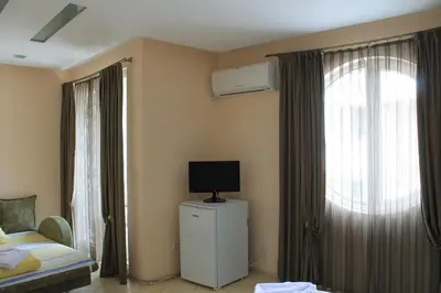 a bedroom with a bed and a tv and a window at Stela Guest House in Tsarevo