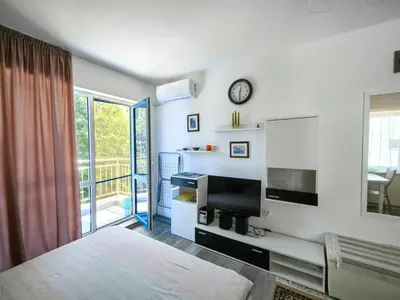 a bedroom with a bed and a television and a balcony at Blu Bey Pomorie in Pomorie