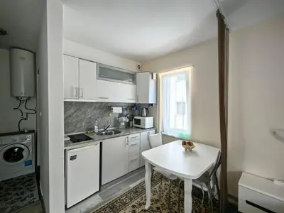 a kitchen with white cabinets and a white table at Blu Bey Pomorie in Pomorie