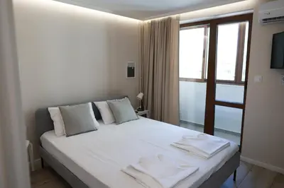 a white bed in a room with a window at Azur Holiday Burgas - self check-in in Burgas City