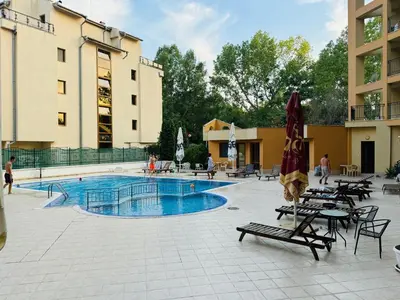 a swimming pool with tables and chairs and an umbrella at AMADEUS I B31 Apartment Sunny Beach in Sunny Beach