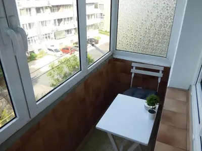 a balcony with a white table and two windows at BOHO Apartment in Varna City