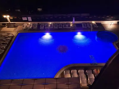 a large blue swimming pool with chairs and lights at Sunny Beach Victoria Penthouse in Sunny Beach