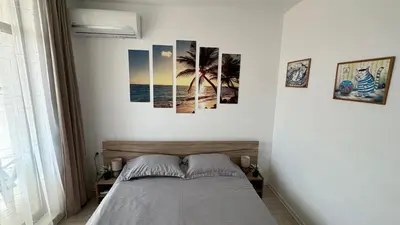 a bedroom with a bed with four pictures on the wall at Apartament Diana in Pomorie
