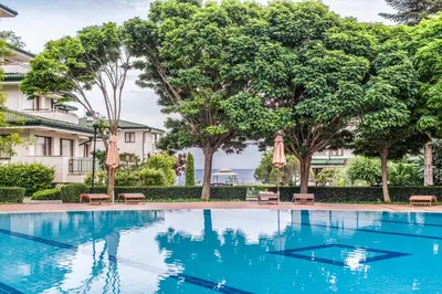 a swimming pool in front of a building with trees at Emerald Beach Resort & Spa in Ravda
