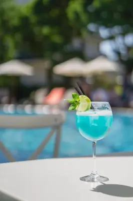 a blue drink in a glass sitting on a table at Emerald Beach Resort & Spa in Ravda