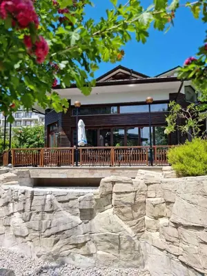 a home with a large wooden porch with a stone wall at Emerald Beach Resort & Spa in Ravda