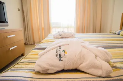 a hotel room with a white towel on a bed at Emerald Beach Resort & Spa in Ravda