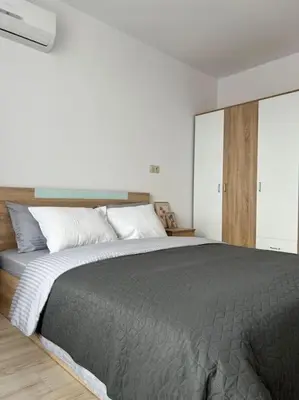 a bedroom with a large bed with a gray blanket at New and stylish apartment Tuthon in Pomorie