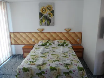 a bedroom with a bed with a floral bedspread at Sianie Guest House in Ravda