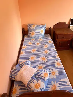 a bed with blue and white sheets with flowers on it at Къща за гости ФОРЕВЪР in Banya