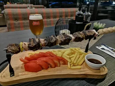 a plate of meat and french fries and a glass of beer at Charming 1 bedroom apartment in Sunny Beach in Sunny Beach