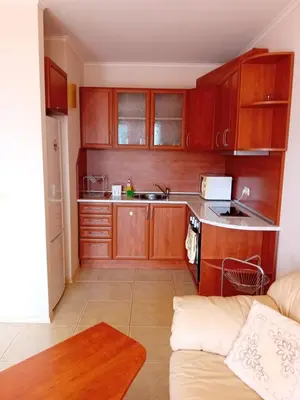 a small kitchen with wooden cabinets and a couch at Златна Дюна - до южния плаж на Несебър in Nesebar