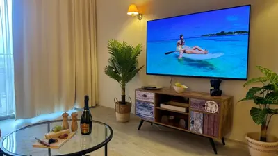 a living room with a tv with a woman on a paddle at Luxury sea view, 5star Barcelo on Beach in Sunny Beach