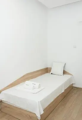 a bed in a room with a white wall at Bright 2-Bedroom Apartment Near Varna City Center by Flat Mаnаger in Varna City