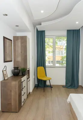 a bedroom with a yellow chair in front of a window at Bright 2-Bedroom Apartment Near Varna City Center by Flat Mаnаger in Varna City