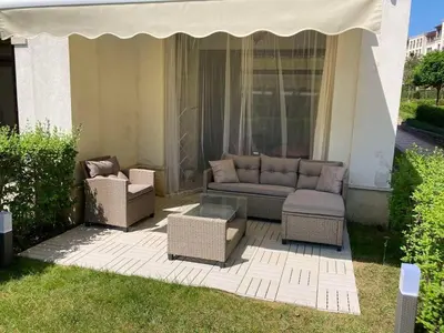 a patio with a couch and chairs and an umbrella at Къща за гости in Kraymorie