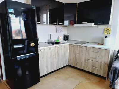 a kitchen with a black refrigerator and wooden cabinets at Guest Apartment Rusalka in Sveti Vlas