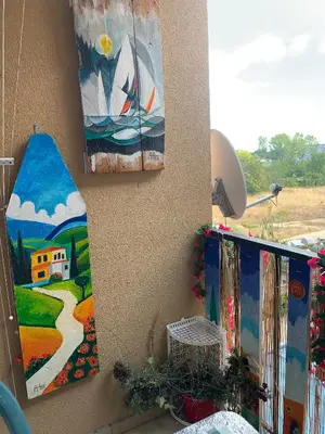 a wall with paintings and a surfboard on it at Студия Мир Авангарда in Sunny Beach