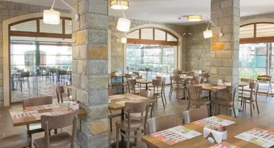 a restaurant with wooden tables and chairs and windows at Luxury Apartment in Cascadas Family Resort Sunny Beach in Sunny Beach