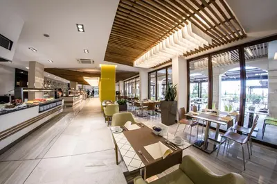 a restaurant with tables and chairs and windows at Premier Fort Cuisine - Full Board in Sunny Beach