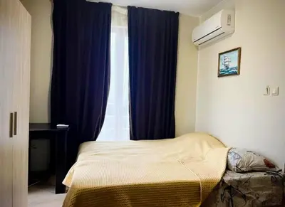 a bedroom with a bed with blue curtains and a window at Апартаменты Мисаря in Sozopol