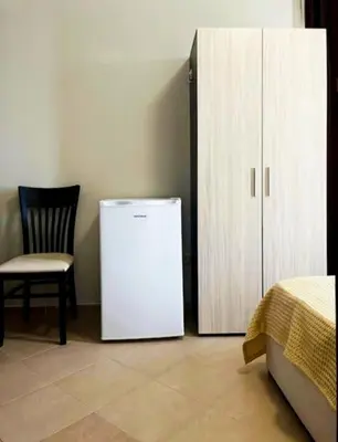 a white refrigerator next to a chair and a cabinet at Апартаменты Мисаря in Sozopol
