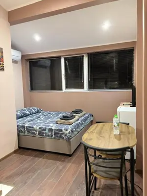 a small bedroom with a bed and a table at GRAND STUDIO SEA GARDEN - top center in Burgas City
