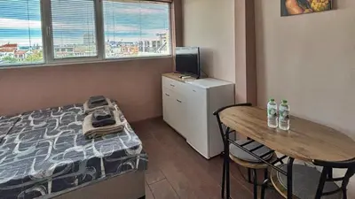 a bedroom with a bed and a table and a desk at GRAND STUDIO SEA GARDEN - top center in Burgas City