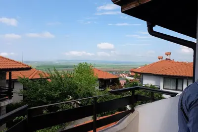a person standing on a balcony looking out at the roofs of houses at Bay View Villas apartment NONA 1C - Kosharitsa in Kosharitsa